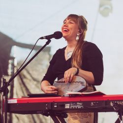 Mari Kalkun mit verschiedenen Instrumenten und einem breiten Lächeln.