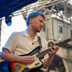 Ein junger Mann mit Gitarre, welcher von unten fotografiert wurde